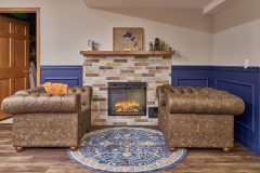 Basement design example with two loveseat chairs facing each other next to a wall fireplace with brown tile accents