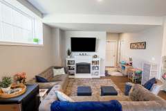 New basement home remodel with blue and gray accent couches and a fireplace with TV lounging area