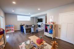 Finished Basement Example with kids play area and mini costume closet. Main area has a couch and family lounging area with a fireplace and tv
