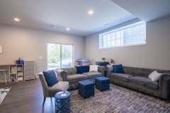 Basement remodel in with blue and gray accent couches ad sliding glass exit to the backyard