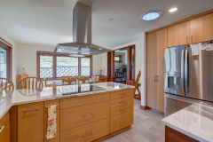 Kitchen remodel showing flat oven and overhead vent in between dining area and kitchen modern wood cabinets