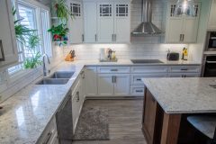 modern kitchen remodeled with white granite counters and cabinets, new steel appliances and lighting fixtures.