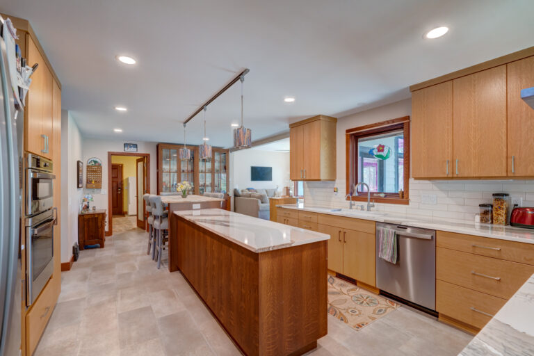 Kitchen remodel with long island. Modern light wood cabinets and new light fixtures. New countertops and dining table