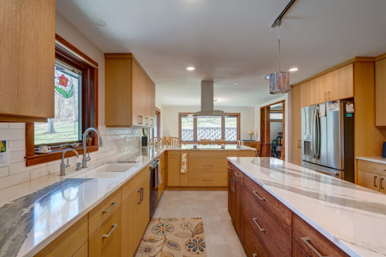 Kitchen remodel with long island. Modern light wood cabinets and new light fixtures