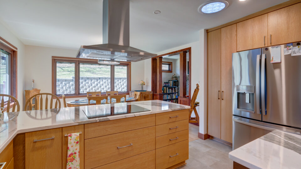 Kitchen remodel showing flat oven and overhead vent in between dining area and kitchen modern wood cabinets