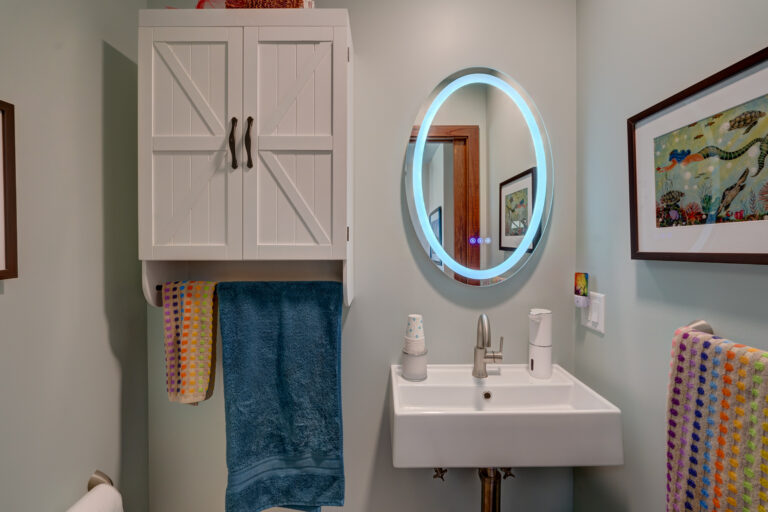 Bathroom remodel showing sink and high tech mirror with lights and cabinet with towel holders