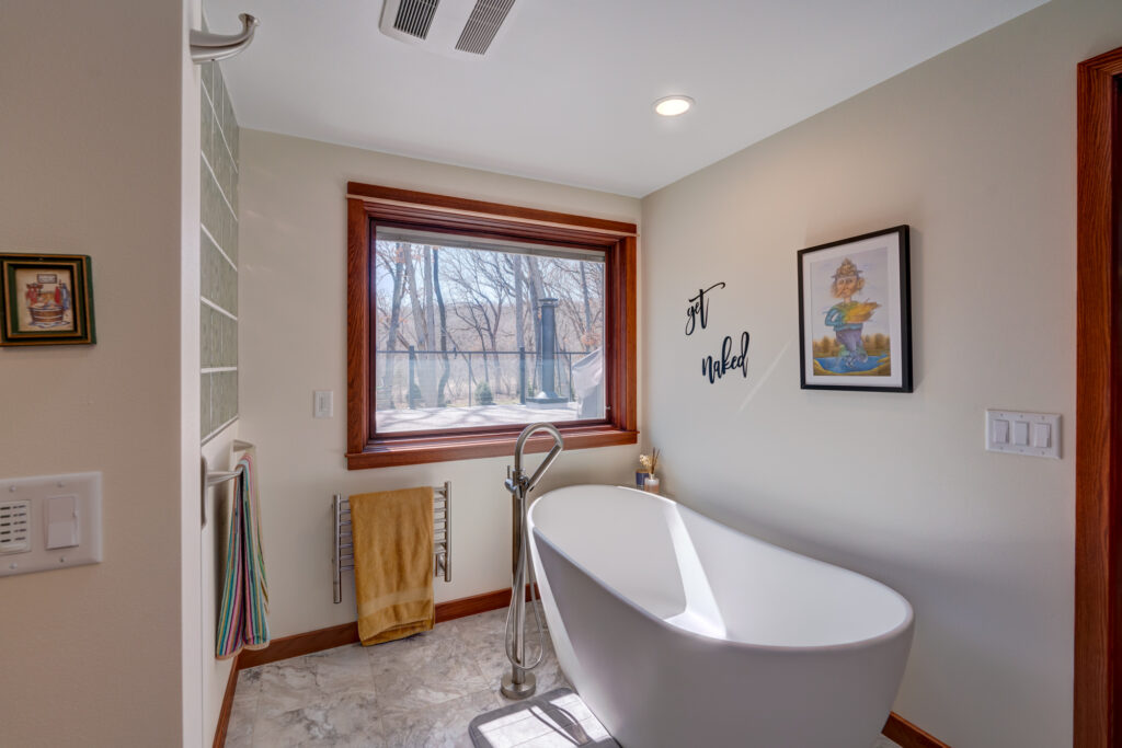 Bathroom remodel with modern freestanding tub and large window with privacy screen